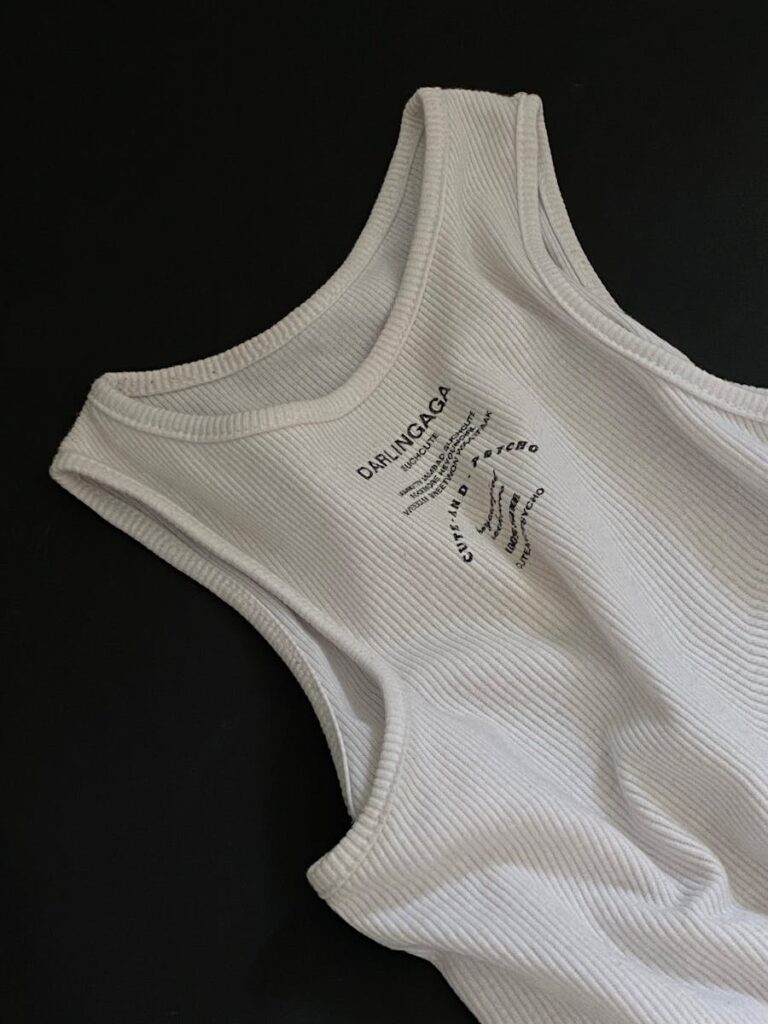 Close-up of a ribbed white tank top on a black surface, minimalist style.