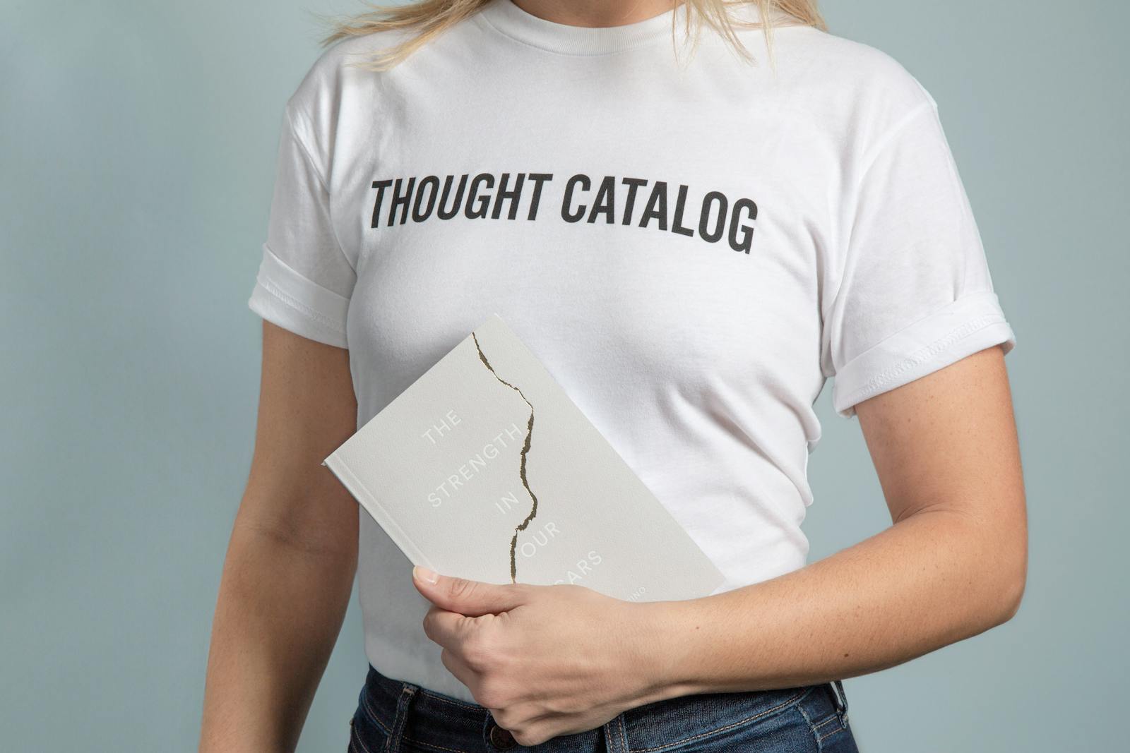 A woman wearing a white t-shirt holds a book with a cracked cover. what is a dtf transfer