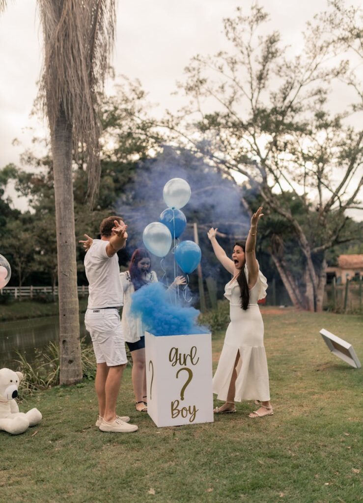 Joyful gender reveal party with blue smoke outdoors, friends celebrating a baby boy.