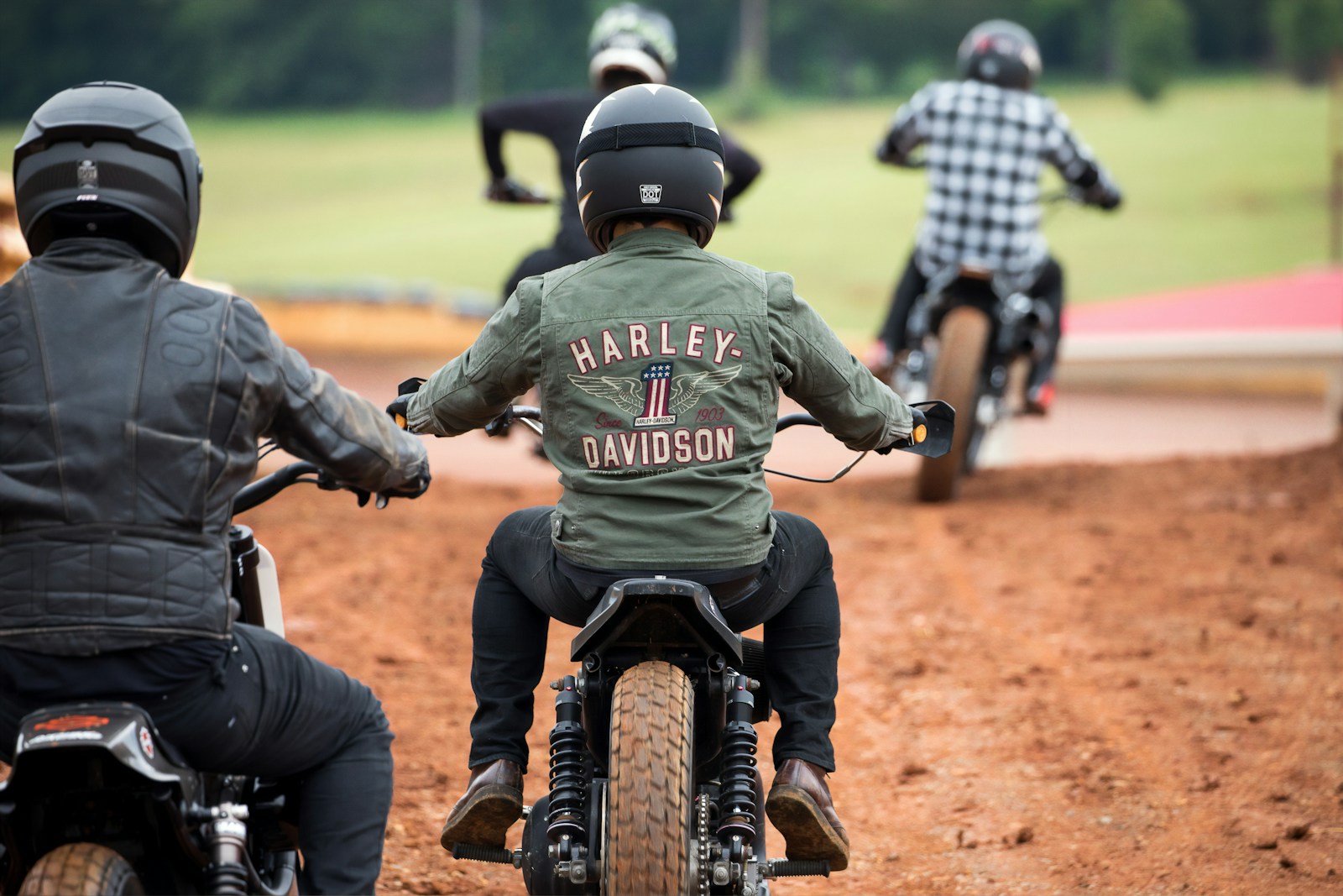 four men riding motocross dirt bikes zip up jackets