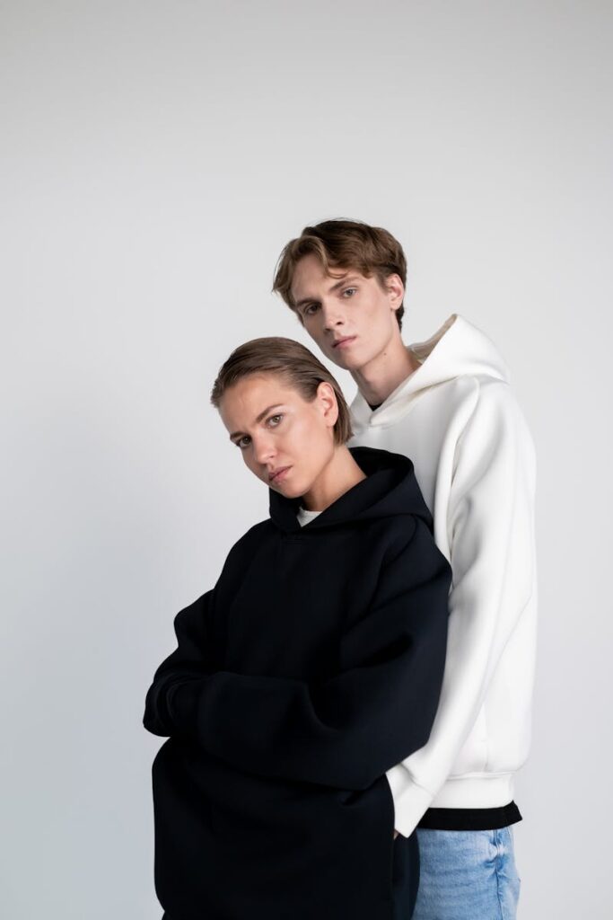 Stylish portrait of a man and woman in casual hoodies against a white background.
