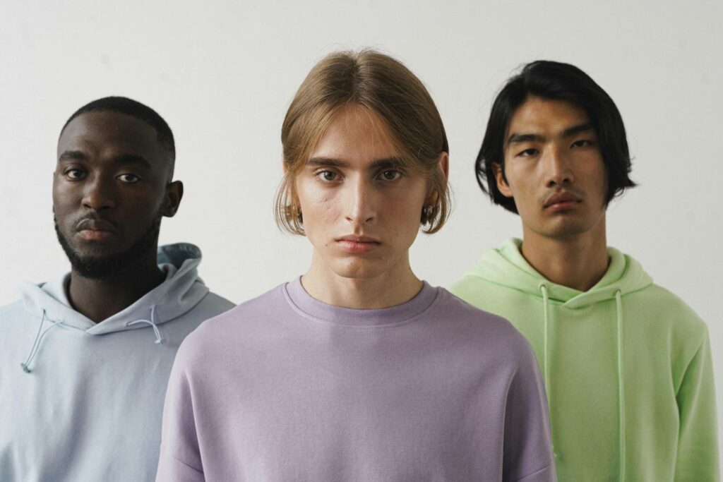 Portrait of three men in pastel hoodies, showcasing simplicity and diversity.