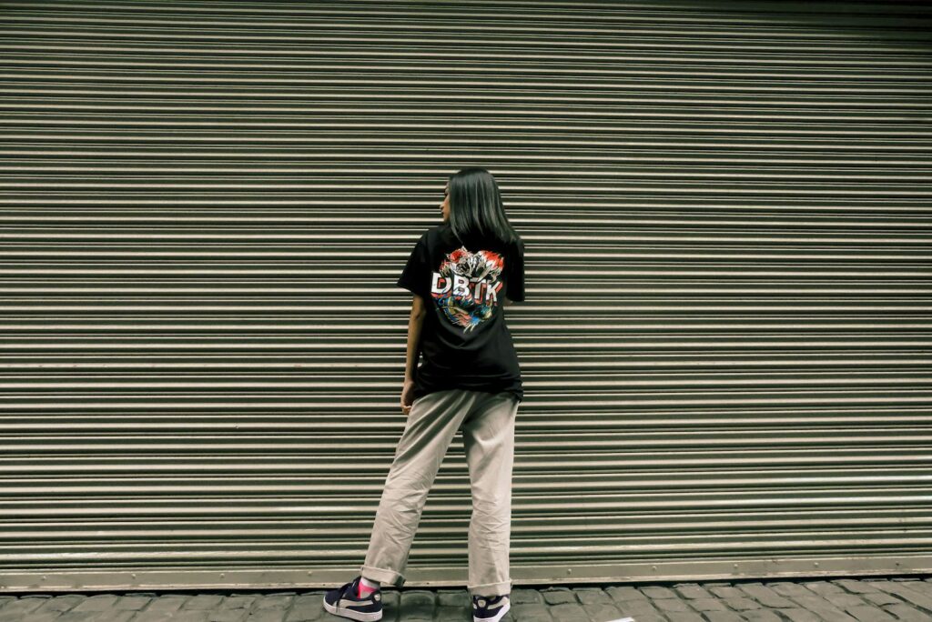 Woman standing in front of a metal shutter wearing casual streetwear.
