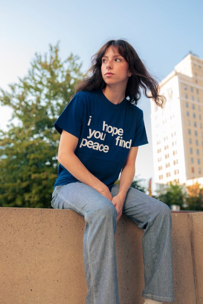 Portrait of young woman in jeans and t-shirt with peace message outdoors.