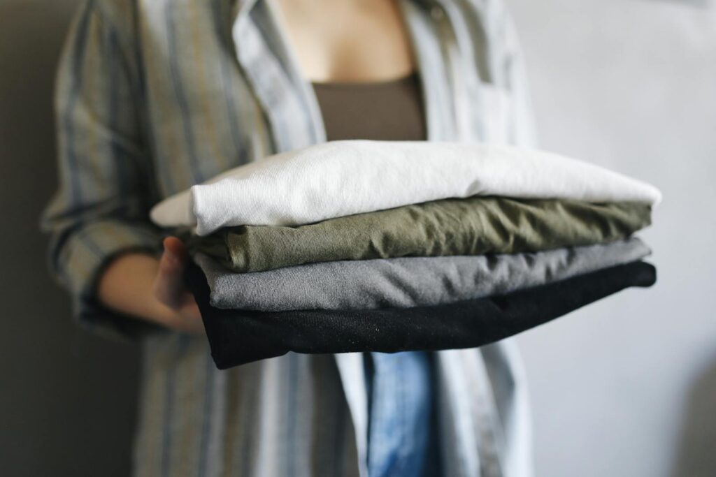 A close-up of a person holding neatly folded shirts, perfect for home organization themes.