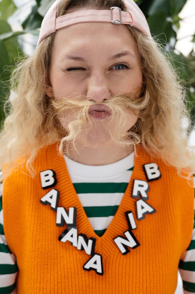 Playful woman with a hair mustache and quirky outfit making a silly expression indoors.