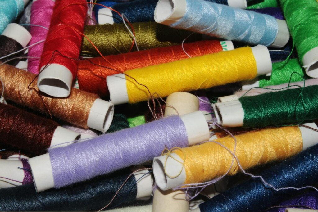 A vibrant collection of colorful sewing threads in spools, essential for tailoring and crafts.