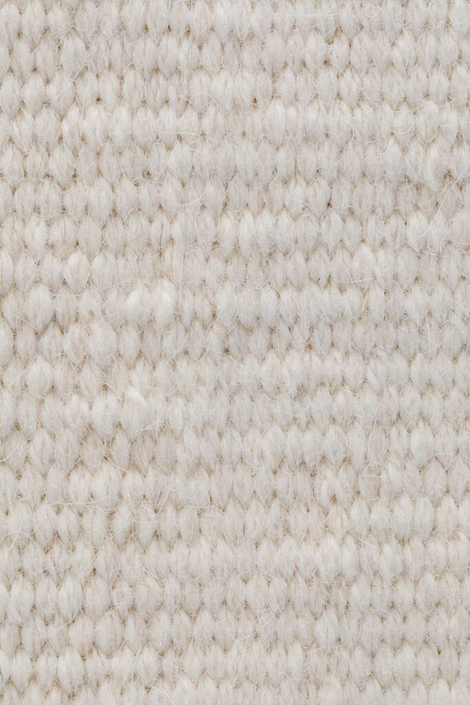 Detailed view of a beige wool textile fabric, showcasing its texture and softness.