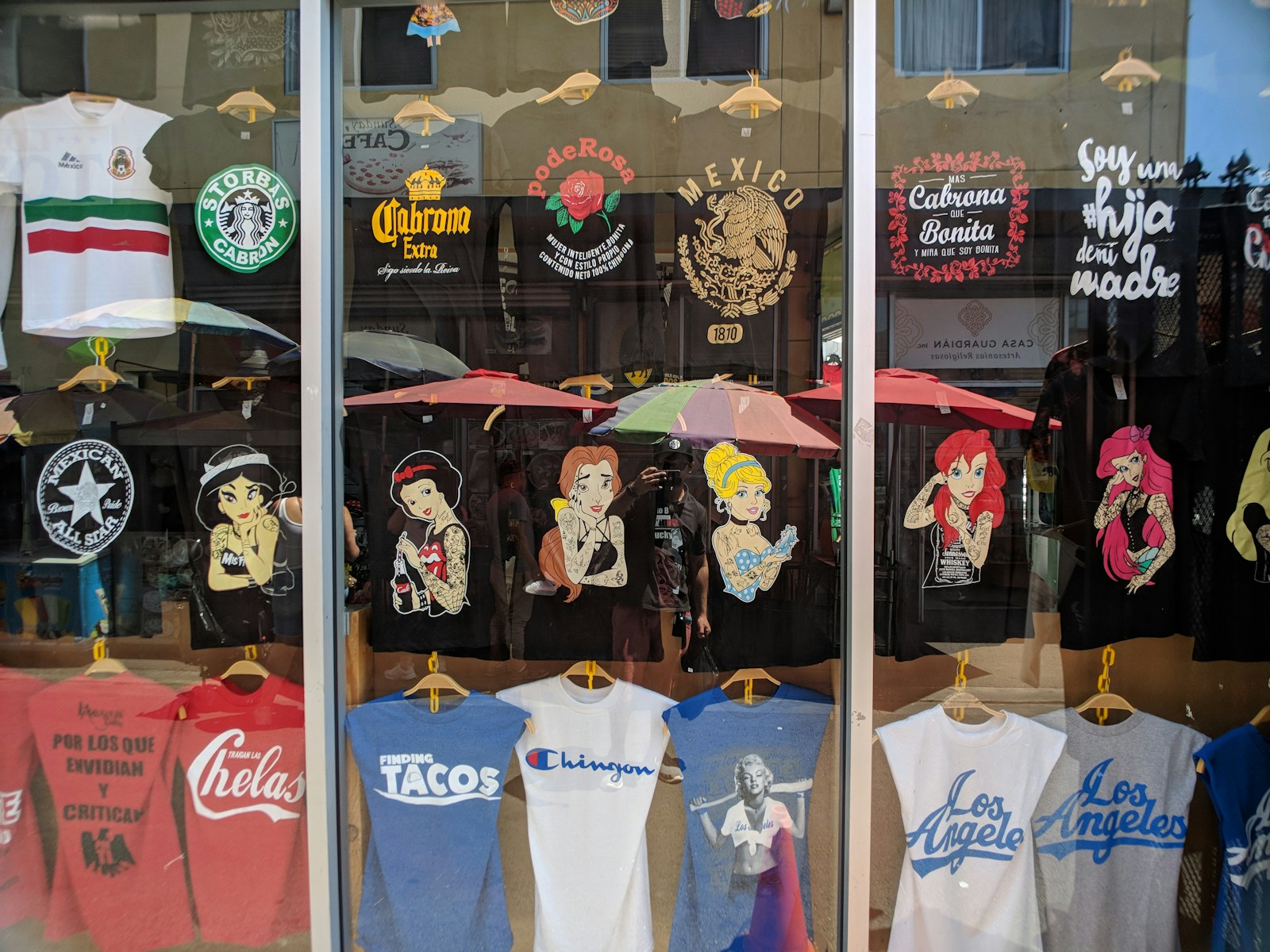 Photo by Akshay Chauhan a store front window with t - shirts and umbrellas (DTF Gang Sheets) | Save Money & Maximize Printing Efficiency