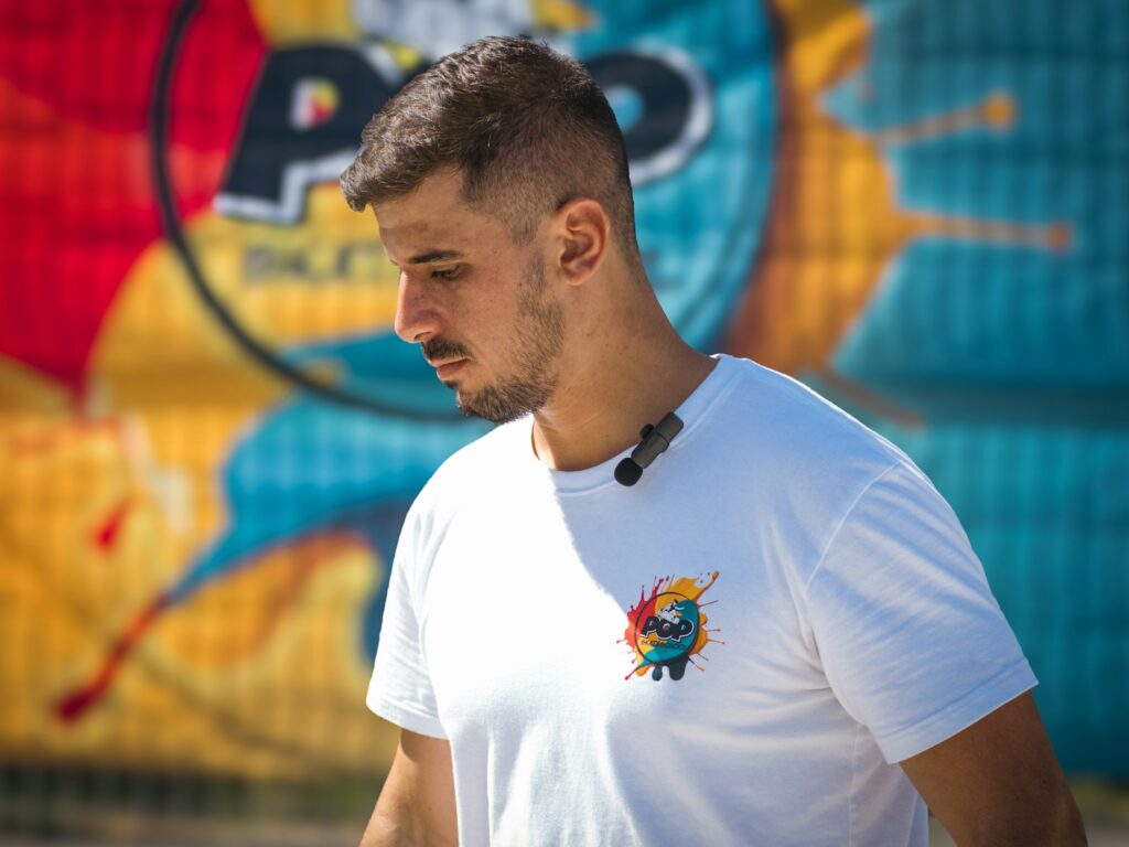 Young man in white t-shirt with cartoon graphic logo.