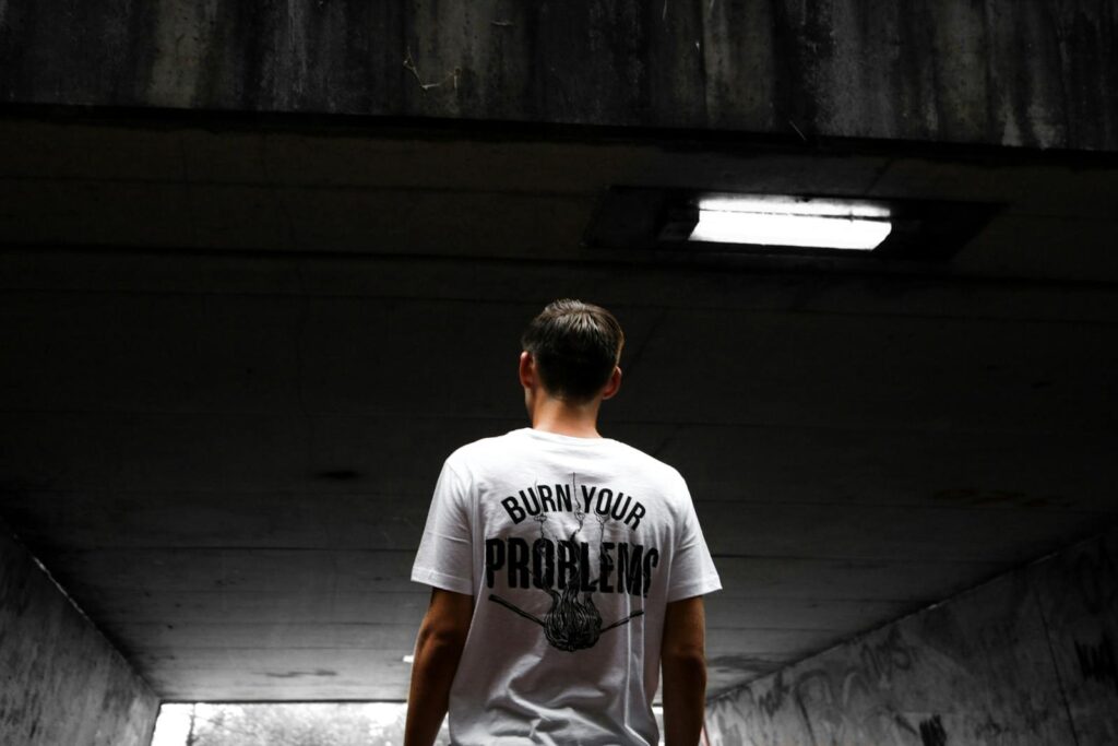 A man stands in an urban tunnel wearing a t-shirt with a bold statement.