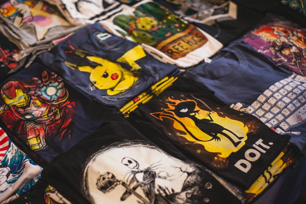 A vibrant assortment of graphic t-shirts featuring popular characters displayed in a market setting. DTF Transfer: How to Get Vibrant, Long-Lasting Prints Every Time