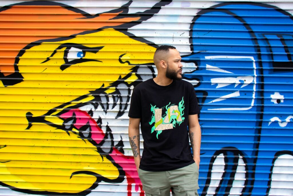 man in black crew neck t-shirt standing beside yellow and blue surfboard