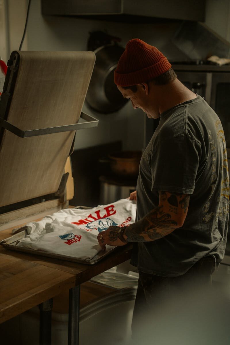 Adult male artist working in a studio, engaging in screen printing on a T-shirt.