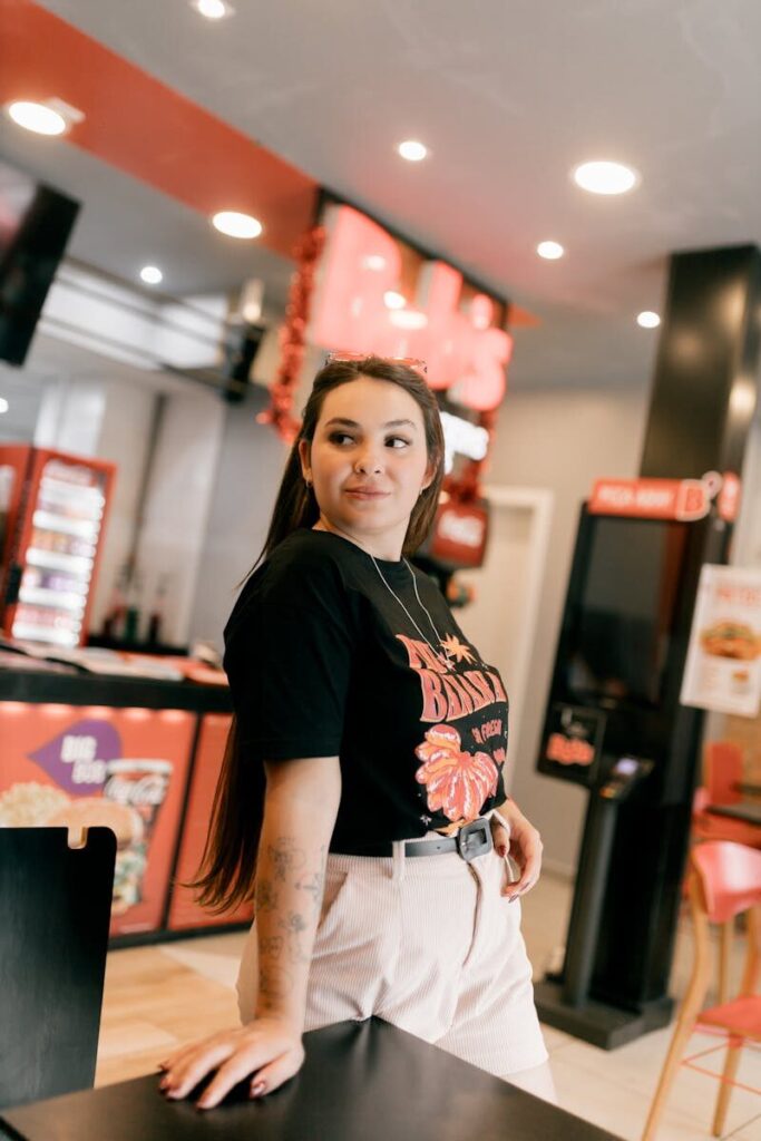 Confident woman in casual attire posing stylishly in a fast food restaurant setting.