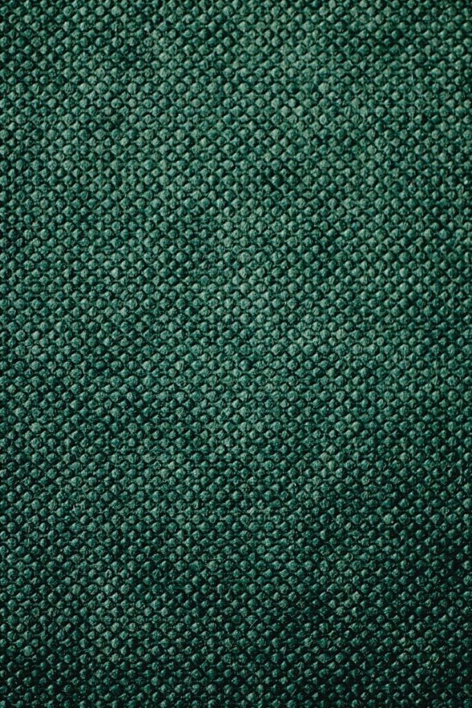 Detailed close-up of green textured textile fabric, showcasing its pattern.