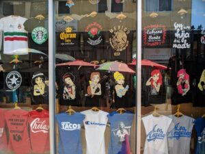 a store front window with t - shirts and umbrellas