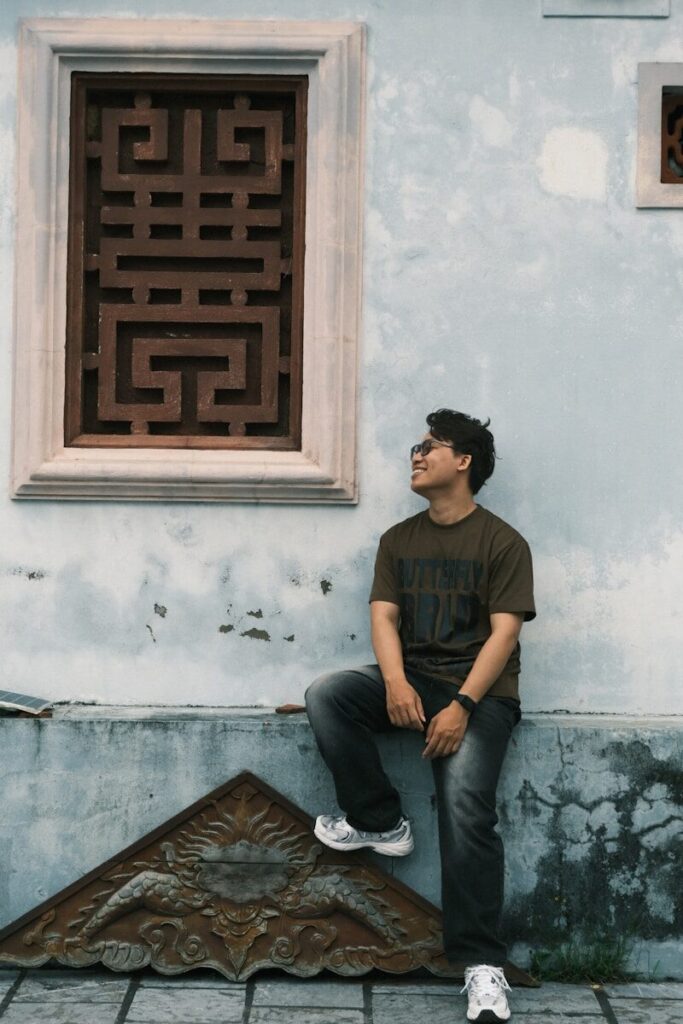 Man leaning against a textured wall with ornate window