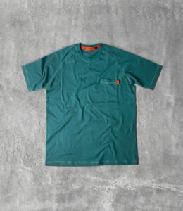 a green t - shirt sitting on a concrete floor