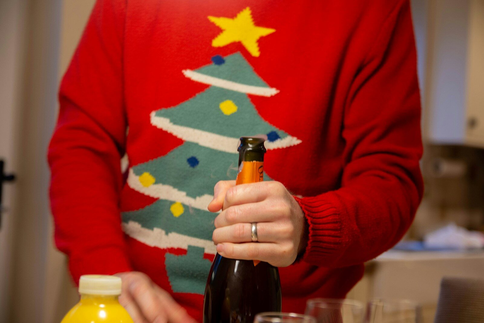 Photo by Richard Bell a person holding a bottle of wine in front of a christmas tree
