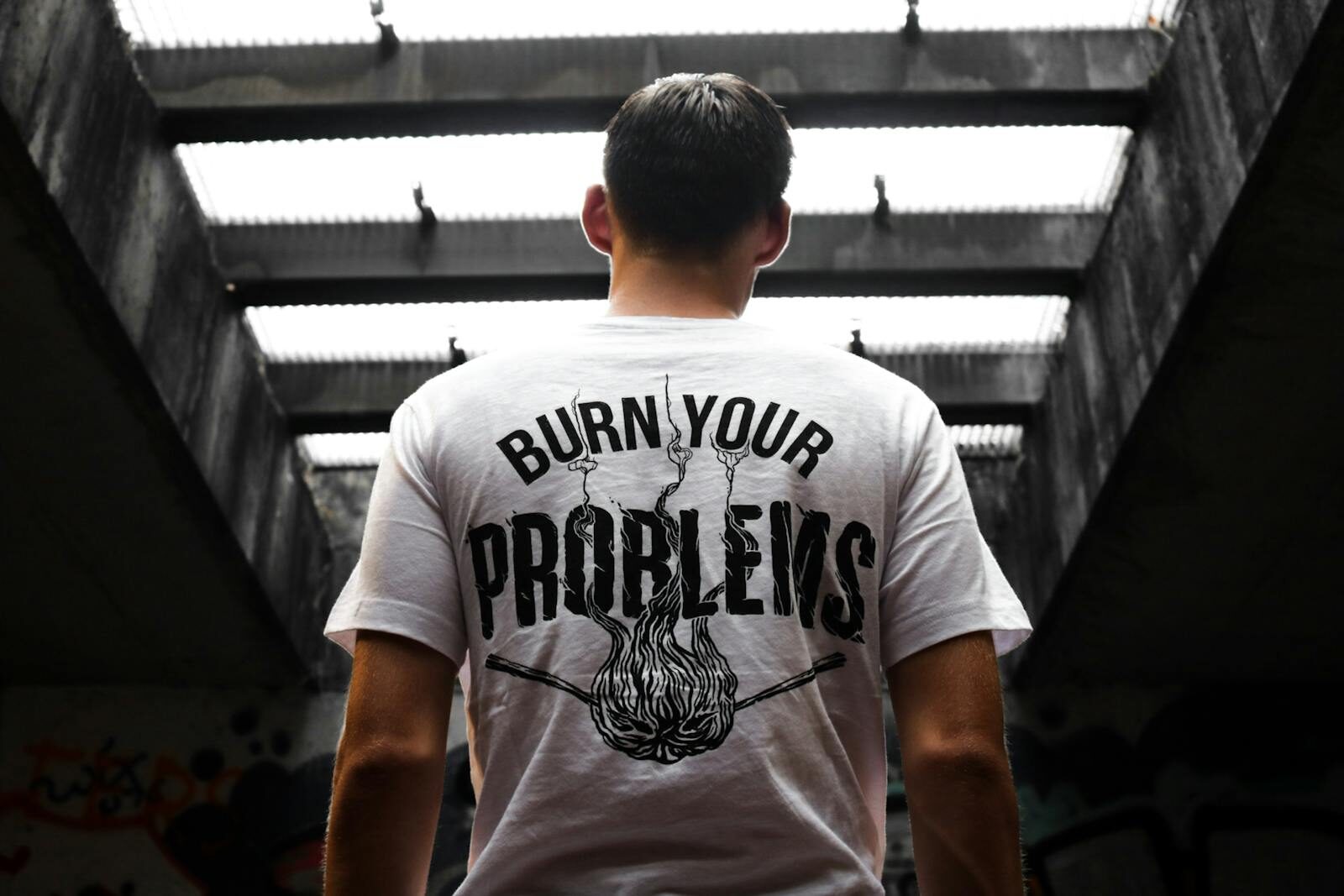 Man standing indoors, wearing a t-shirt with 'Burn Your Problems' text, viewed from behind. DTF Sheets Guide: Everything You Need to Know Before Ordering