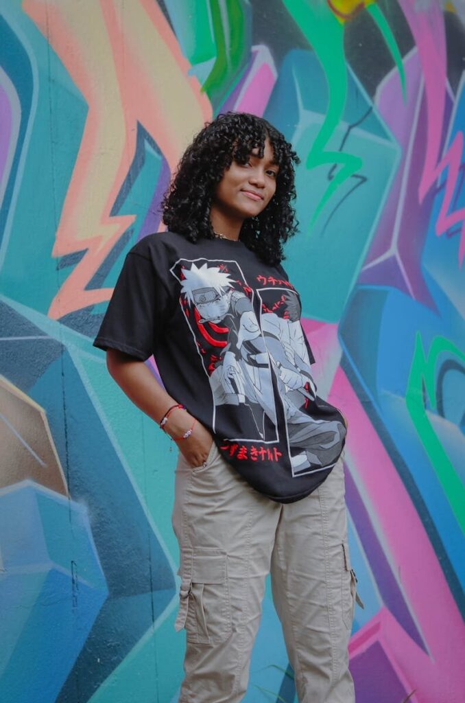 Teen girl posing confidently in front of a colorful urban mural, showcasing modern street fashion.