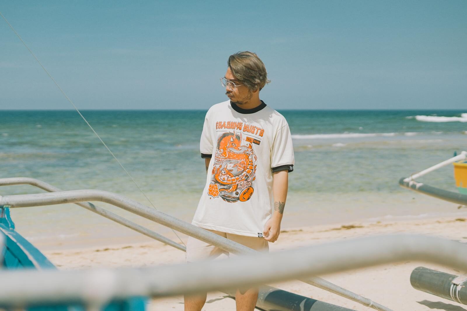 Man in graphic t-shirt standing on the beach near the ocean shore. DTF Designs: How to Create High-Quality Prints That Sell