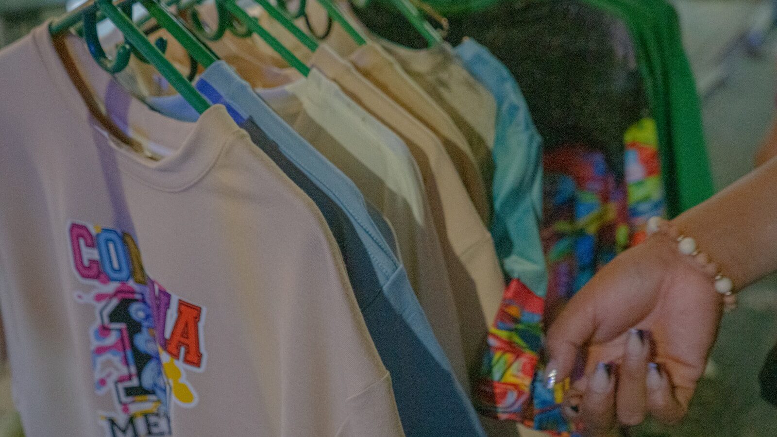 A woman is holding onto a t - shirt hanging on a rack Direct to Film Transfers Mistakes: What to Avoid for Perfect Prints