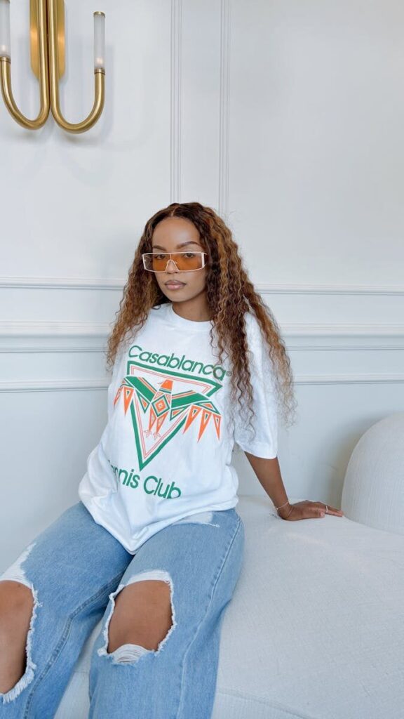Stylish woman in graphic Casablanca tee with trendy sunglasses indoors.