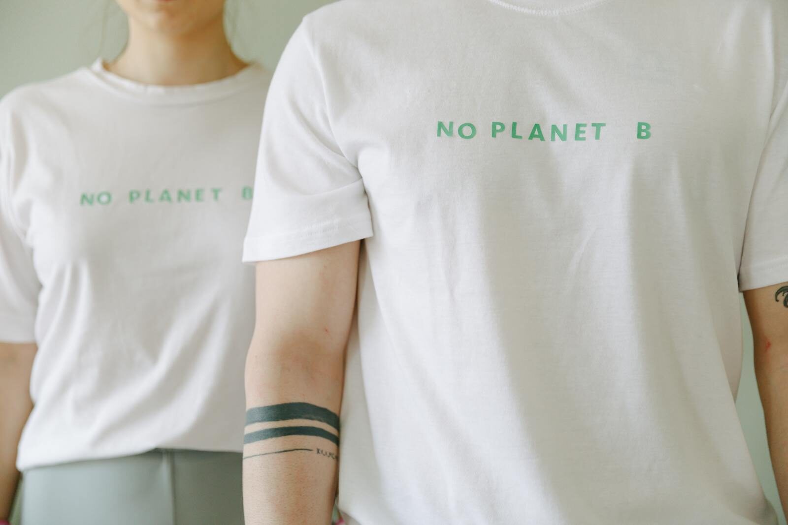 Close-up of two people wearing white 'No Planet B' T-shirts, promoting environmental awareness. DTF Transfer Process: From Design to Finished Garment