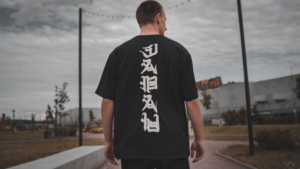 man in black and white crew neck t-shirt standing on gray concrete pavement during daytime DTF Transfers Durability: How Long Do They Really Last?