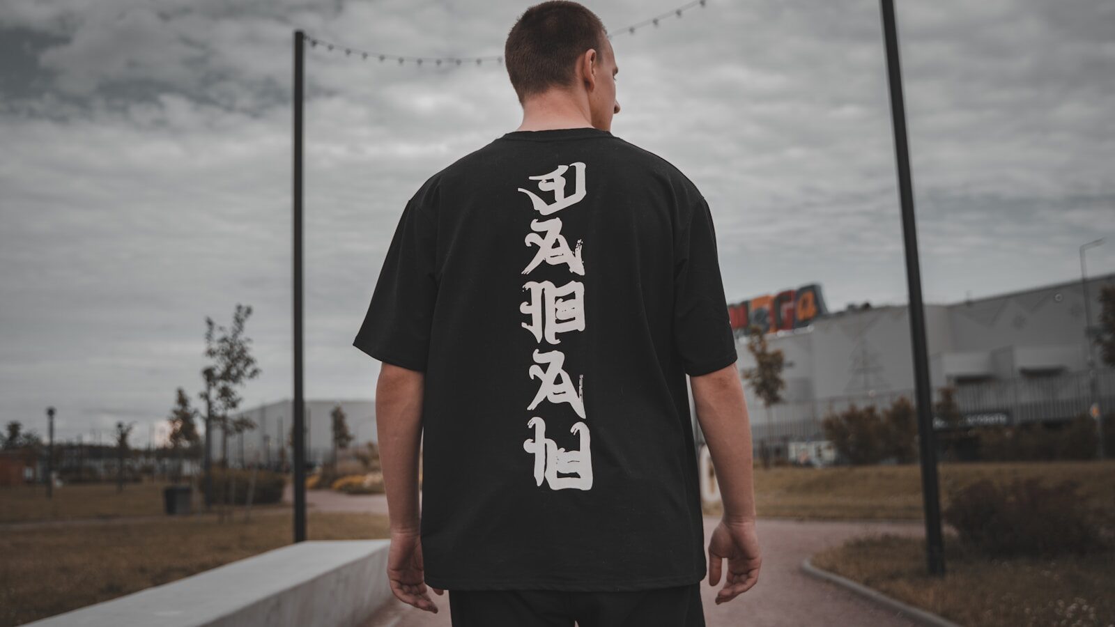 man in black and white crew neck t-shirt standing on gray concrete pavement during daytime DTF Transfers Durability: How Long Do They Really Last?