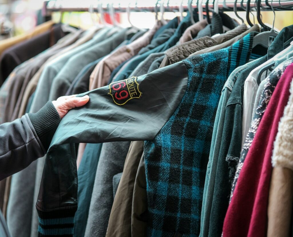 a person holding a shirt in front of a rack of shirts