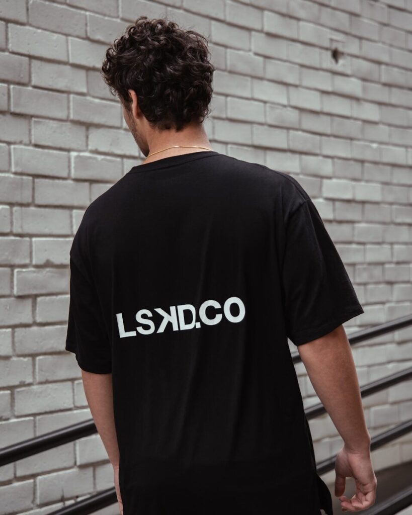 man in black crew neck t-shirt standing near brick wall