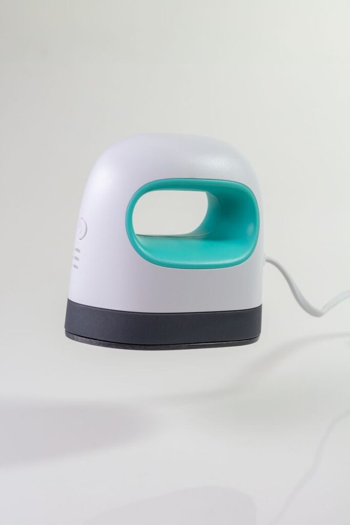 Minimalist image of a small white and green iron levitating, showcasing modern design.