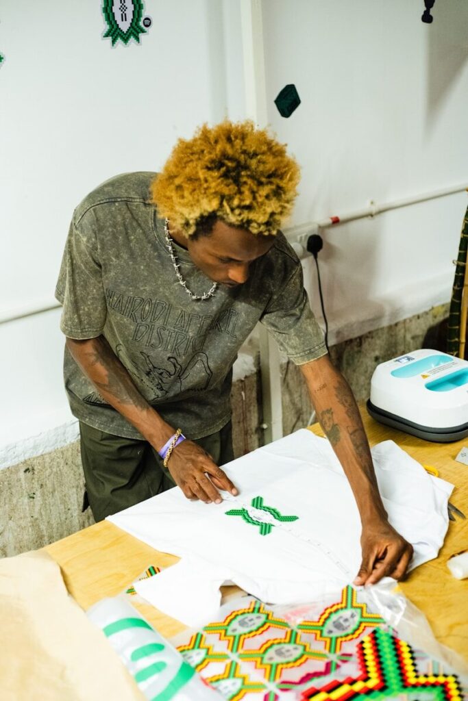 Young man applying a green design to a white t-shirt.