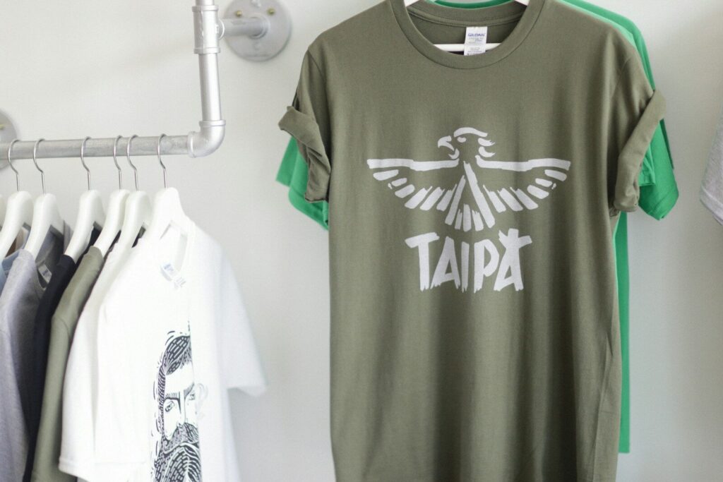 a t - shirt hanging on a rack next to clothes