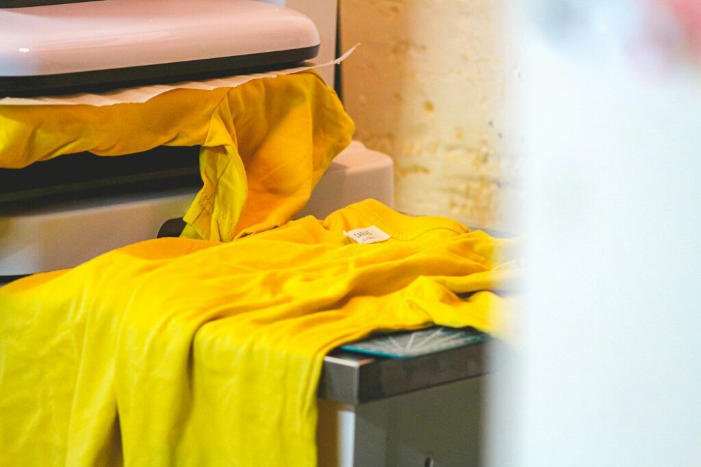 A yellow t-shirt on a pressing machine.