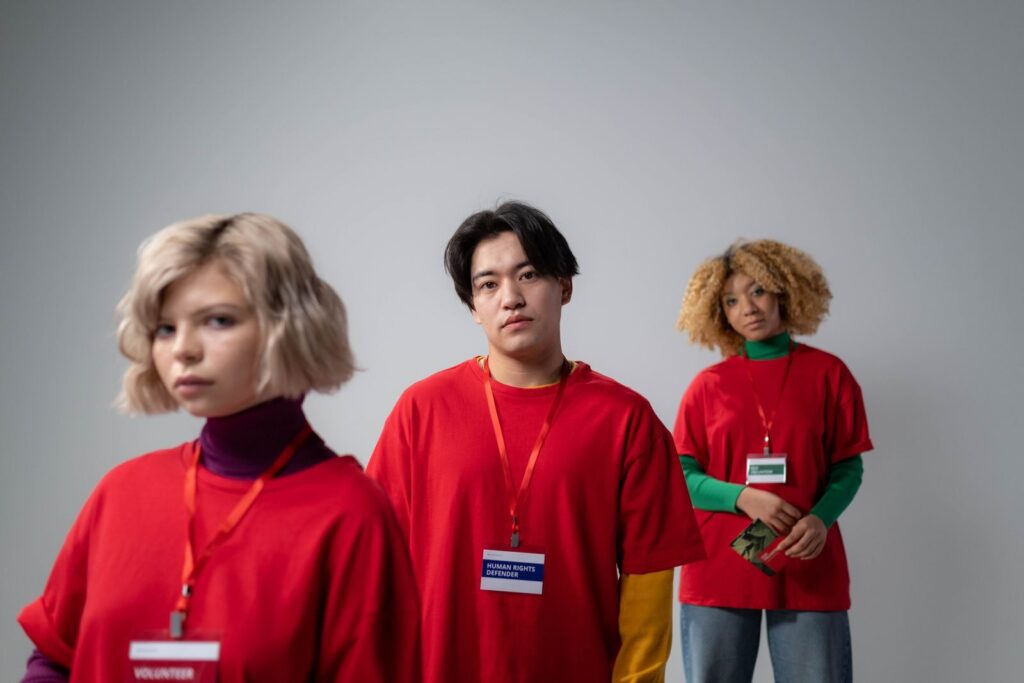 Three volunteers in red shirts engaged in service work, showcasing diversity and teamwork.