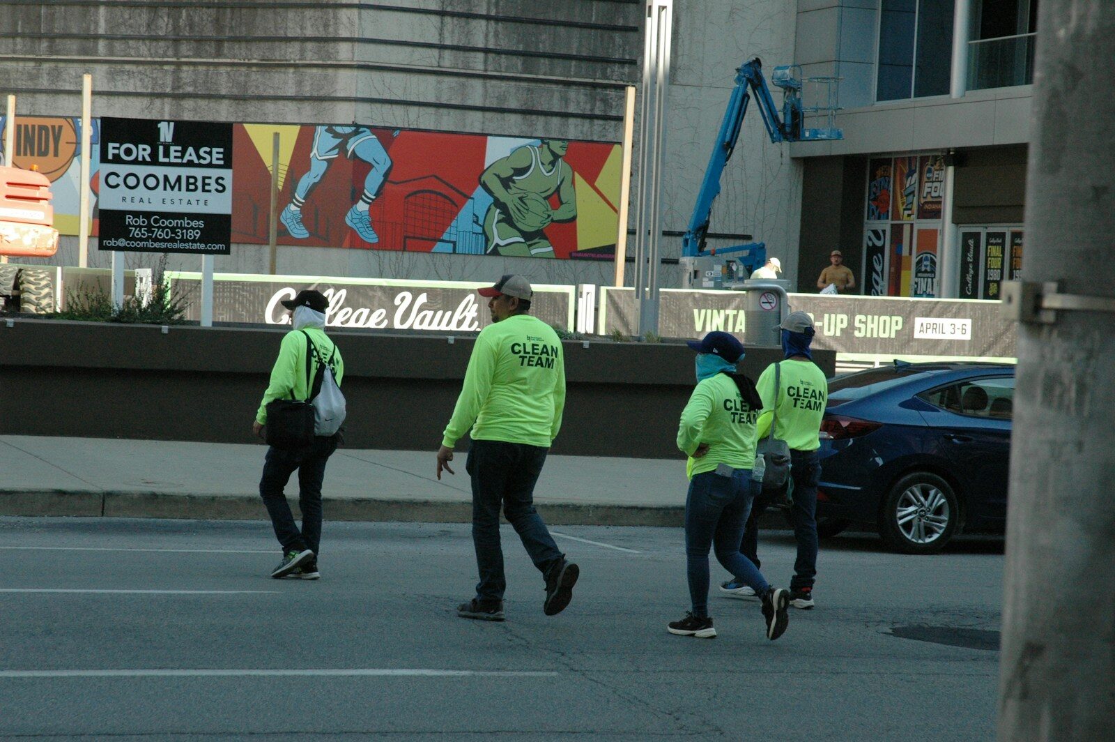 Four people in neon vests cross a street