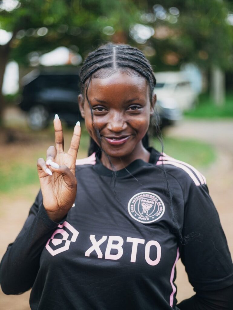 Young black woman in soccer jersey making peace sign