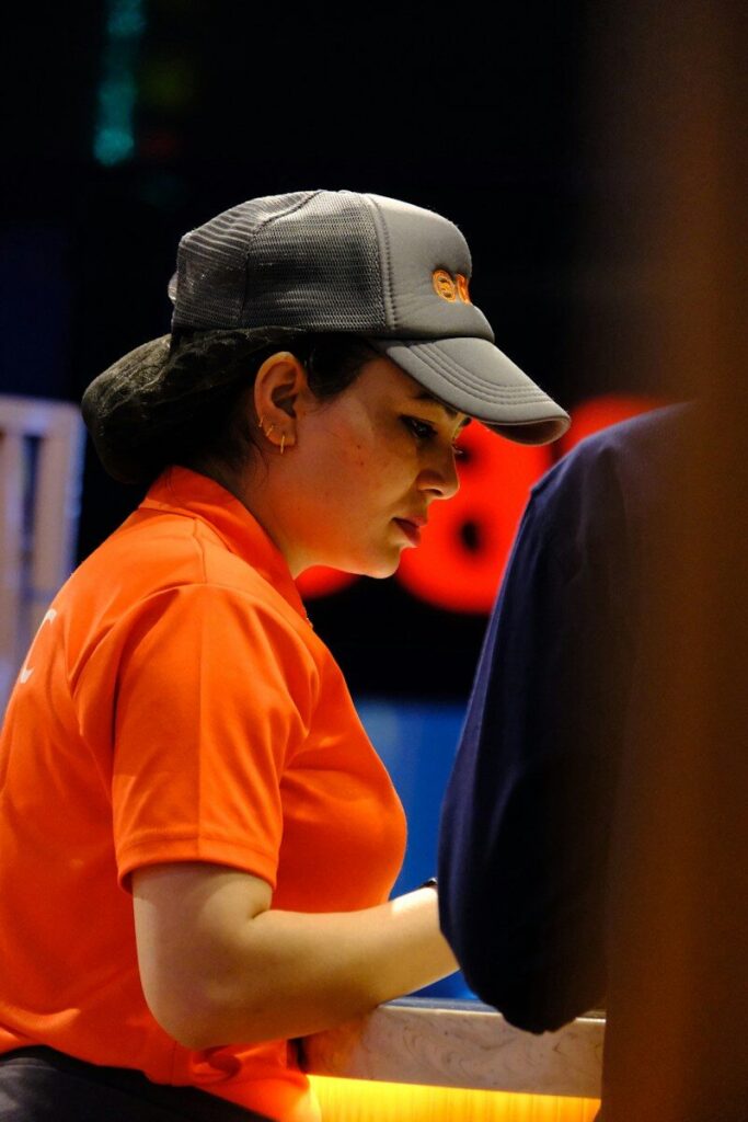 Woman in orange shirt and grey cap working